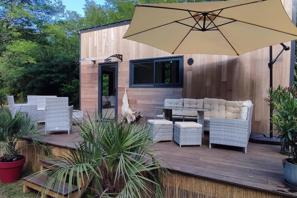 a patio with a table and chairs and an umbrella at Tiny house chez Caroline in Gaillan-en-Médoc