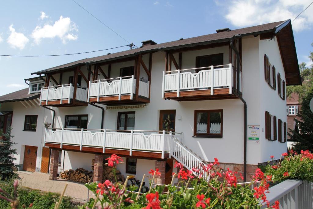 um edifício de apartamentos branco com varandas e flores em Schönes Doppelzimmer mit separater Küche im nördlichen Nationalpark Schwarzwald em Forbach