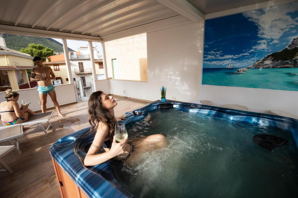 a woman sitting in a hot tub with a glass of wine at Hotel San Francisco in Cala Gonone