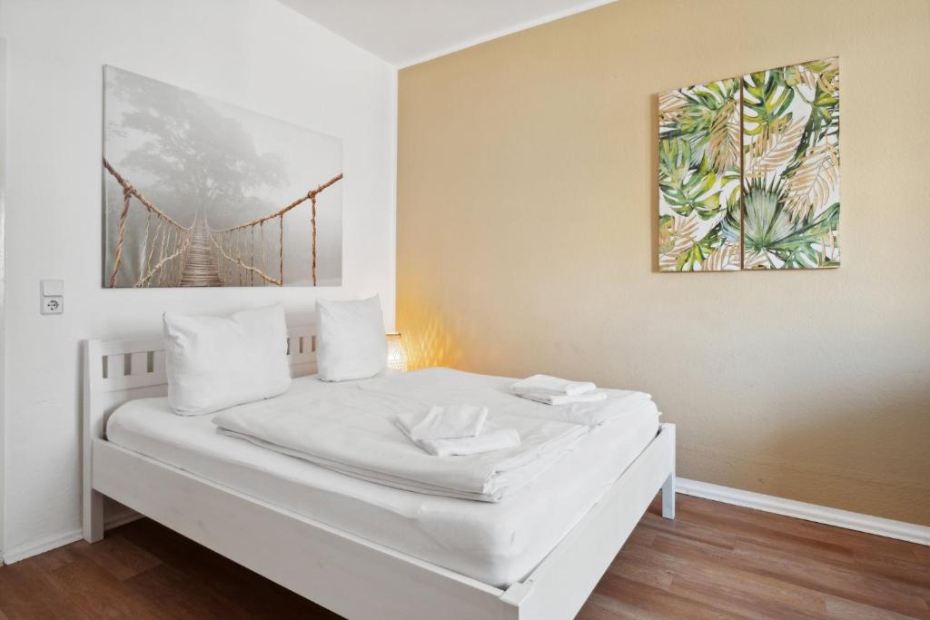 uma cama branca num quarto com uma pintura na parede em Cozy flat near Ku'damm with free parking em Berlim