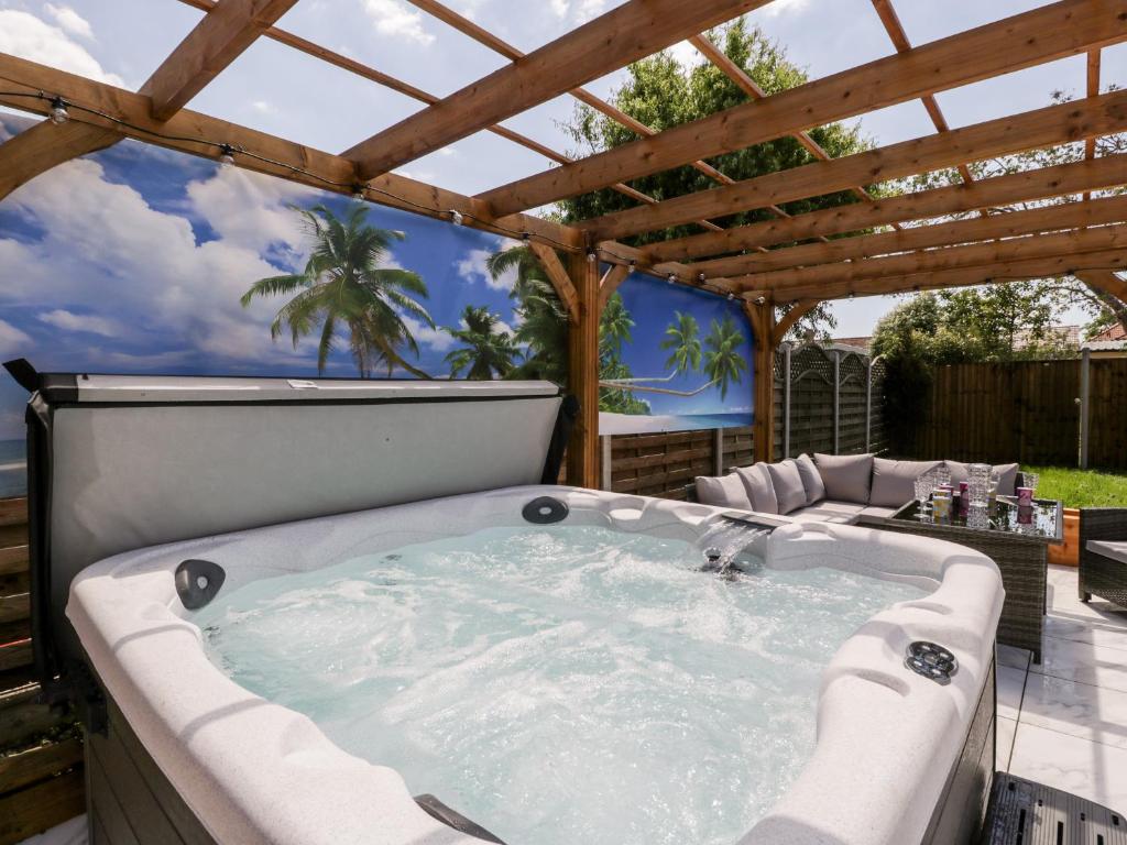 a hot tub in a patio with a pergola at Seacider in Burnham on Sea