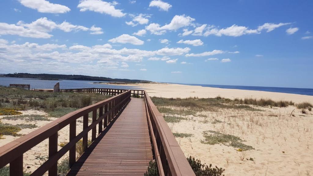 un paseo marítimo de madera que conduce a una playa con el océano en Lagoa Beach & Leisure en Costa de Santo André