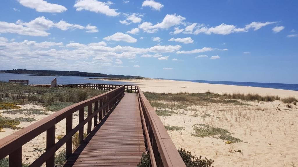 un paseo marítimo de madera que conduce a una playa con el océano en Lagoa Beach & Leisure, en Costa de Santo André
