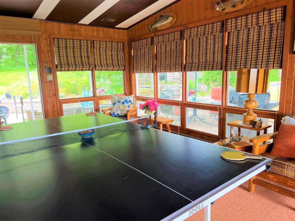 a large ping pong table in a room with windows at Somewhere In Time - RETRO SPACIOUS COTTAGE with PRIVATE SANDY BEACH in Wiarton
