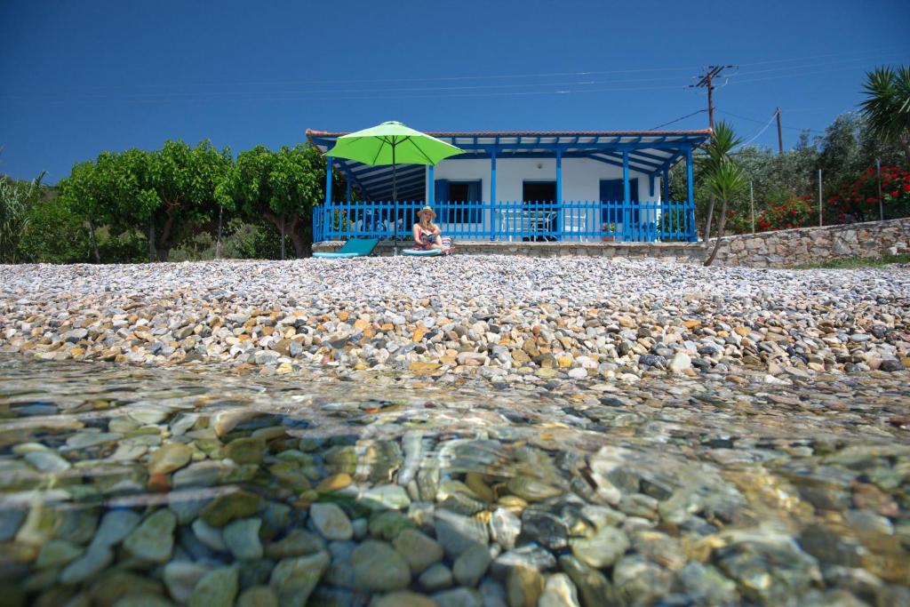 Mourterón的住宿－Seahorse cottage，坐在岩石海滩上伞下的女人