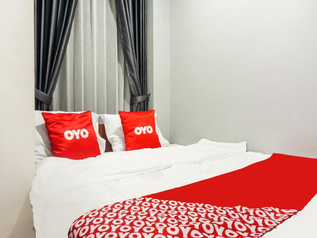 a bed with two red pillows on it at Collection O 91226 M'kostel Syariah in Serang