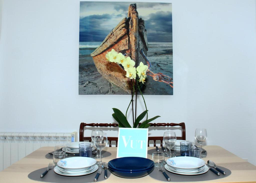 une table avec des assiettes et un vase avec des fleurs. dans l'établissement Apartamento R Y C, à Avilés