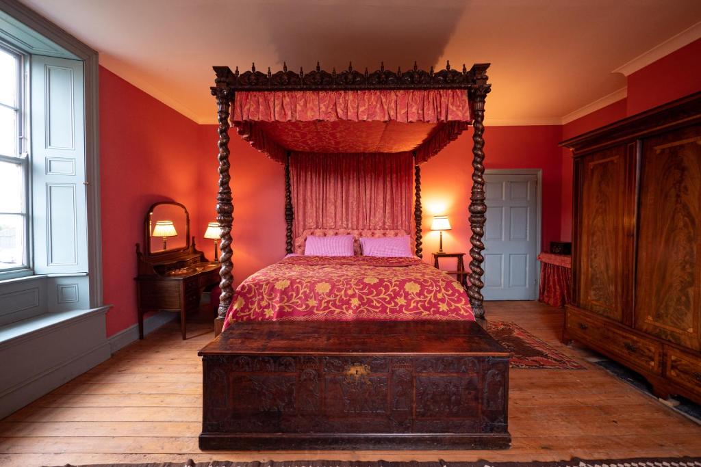 a bedroom with a canopy bed and red walls at Sawcliffe Manor Country House with Spa, Free Parking, Catering, Self Checkin, Farmstay in Scunthorpe