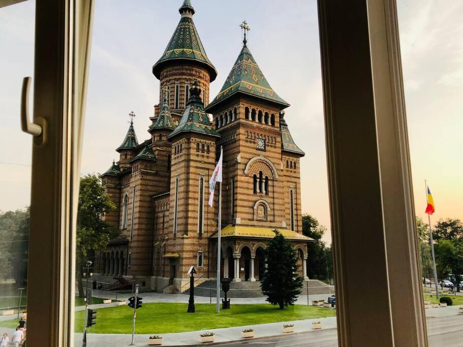 uma janela com vista para um edifício com uma torre de relógio em Joy City Stay Victoriei 7G-3 em Timisoara