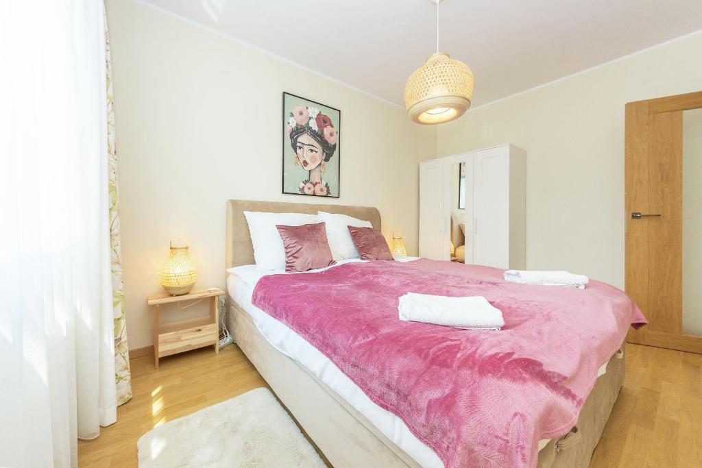 een slaapkamer met een groot bed en een roze deken bij Pomorskie Apartamenty Bernadowska Green Deluxe in Gdynia