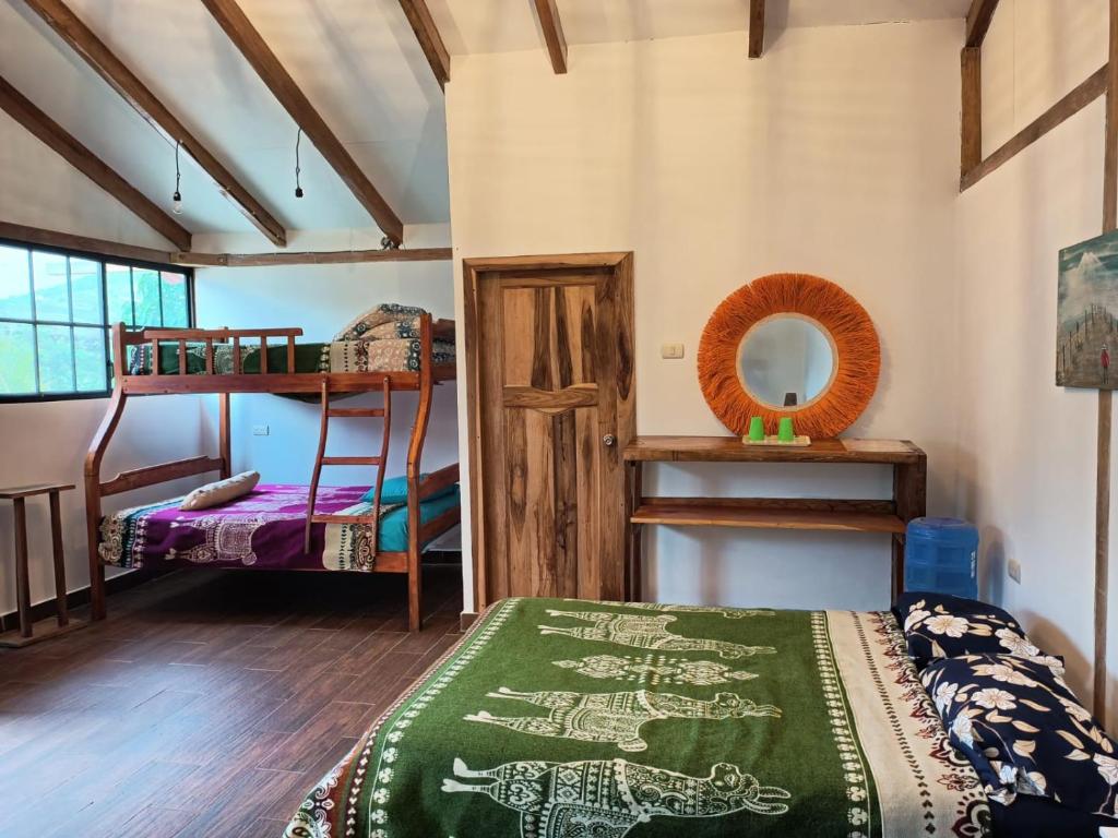 a room with bunk beds and a bed with a green blanket at Café Madame in Puerto López