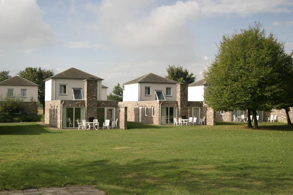 una gran casa con mesas y sillas en un patio en Bungalowpark Landsrade en Gulpen