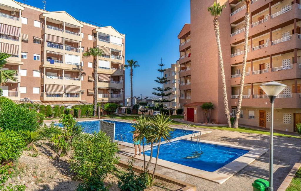 einem Pool vor einem Gebäude mit Palmen in der Unterkunft Nice Apartment In Arenales Del Sol With Kitchen in Elche