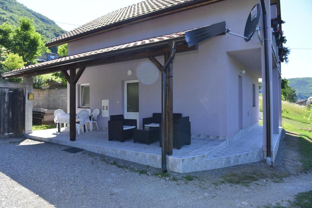 Cette maison dispose d'une terrasse couverte avec une table. dans l'établissement Kuca za odmor Dragina, à Perućac