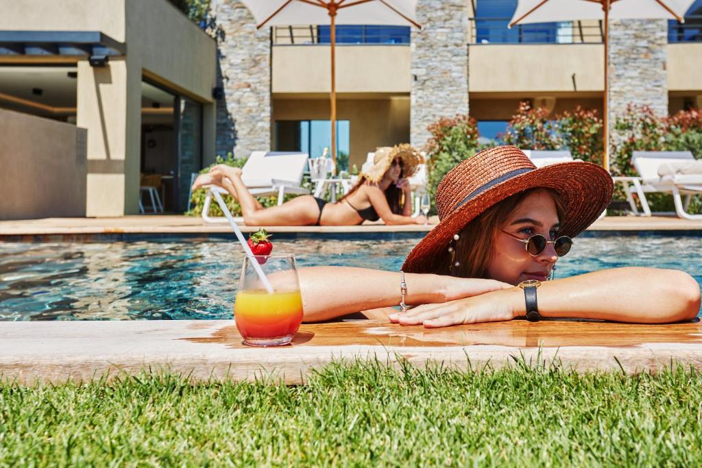 a woman in a hat laying by a pool with a drink at EDEN HÔTEL in Sainte-Maxime