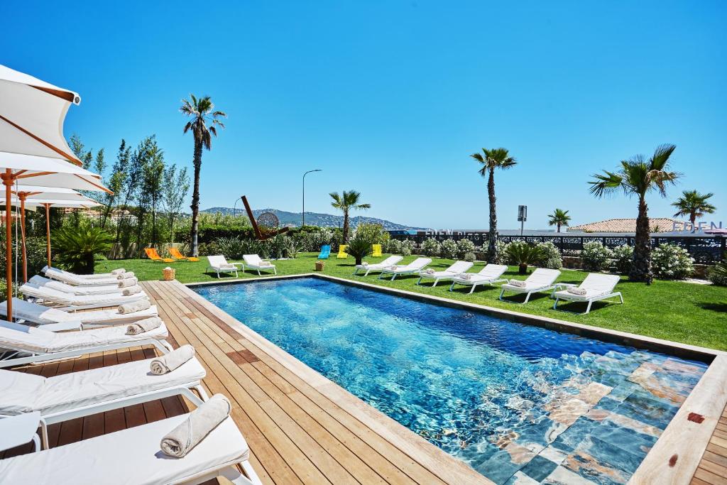 uma piscina com espreguiçadeiras brancas e um visor de piscina em EDEN HÔTEL em Sainte-Maxime