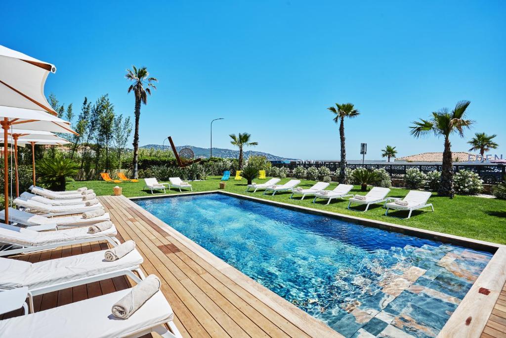 - une piscine avec des chaises longues blanches et un salon de natation dans l'établissement EDEN HÔTEL, à Sainte-Maxime