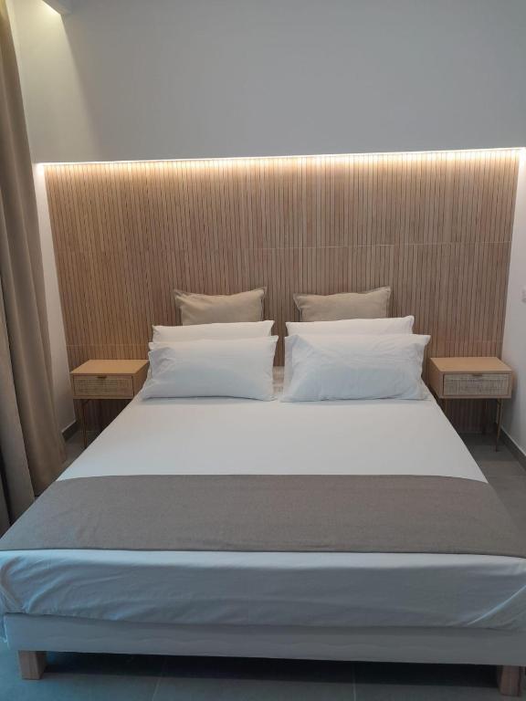 un letto con lenzuola e cuscini bianchi in una stanza di BAARIA House Hotel a Barcellona Pozzo di Gotto
