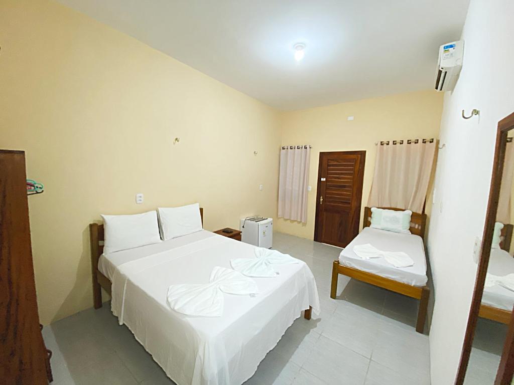 a bedroom with a large white bed and a chair at Morada da Praia Pousada in Jericoacoara