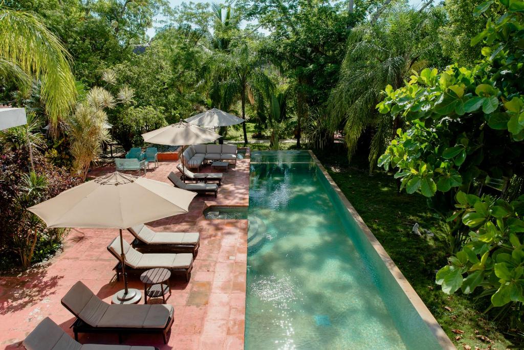 a swimming pool with lounge chairs and umbrellas at Coco Hacienda Tulum - Adults Only in Tulum