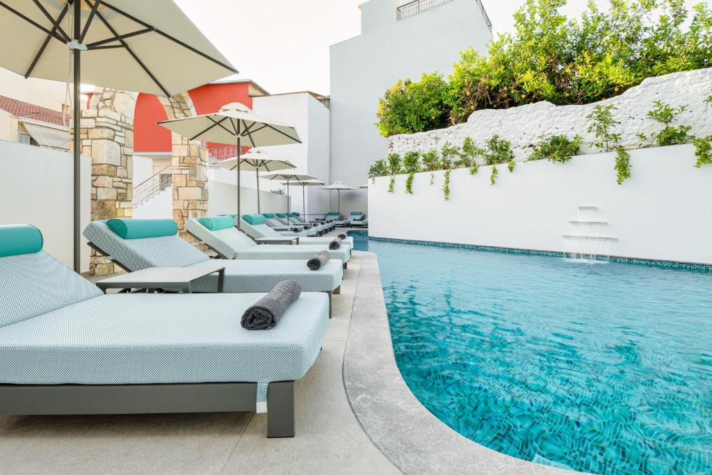 a pool with chairs and umbrellas next to a swimming pool at Dioni Boutique Hotel in Preveza