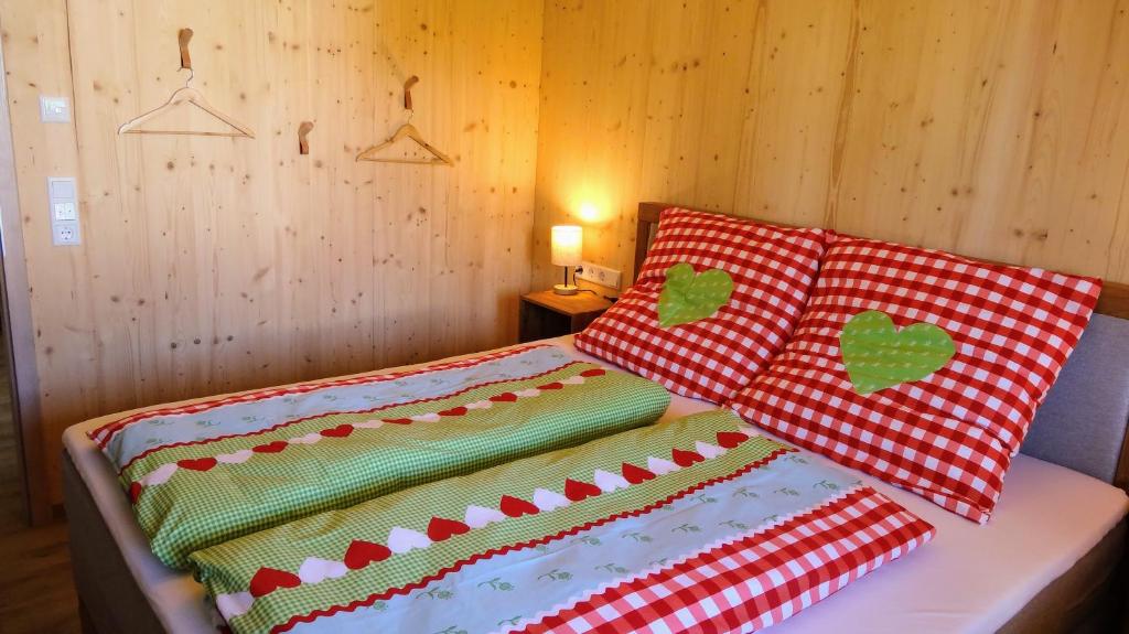 Una cama con dos almohadas rojas y blancas. en WaldBlick im Happy Allgäu - Wohnung mit großer Dachterrasse, en Leutkirch im Allgäu