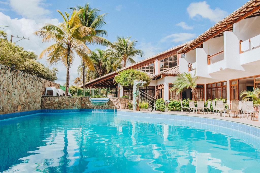 una piscina frente a una casa con palmeras en Poty Praia Hotel, en Porto Seguro