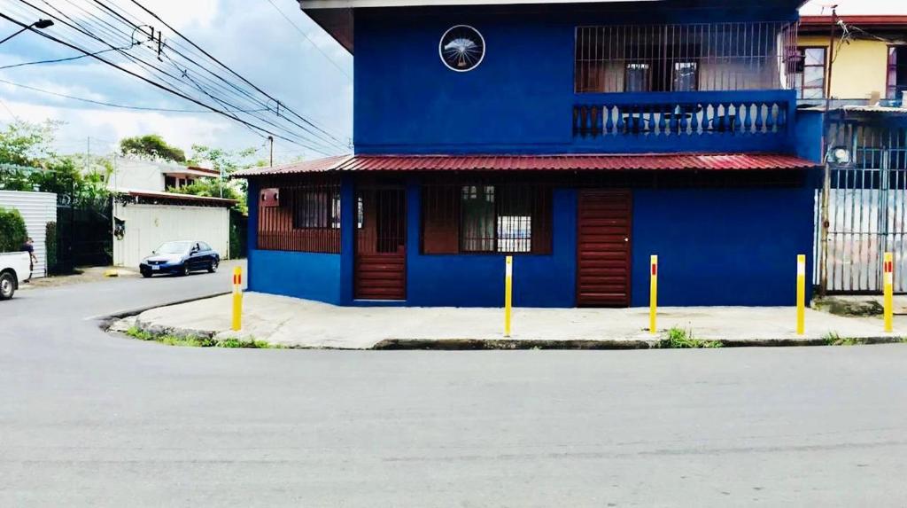ein blaues Gebäude mit einem davor geparkt in der Unterkunft Casa Bambú Tropical in Alajuela
