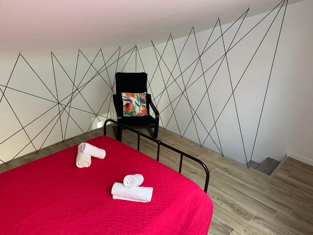 um quarto com uma cama vermelha e 2 toalhas brancas em CASA DAS CEGONHAS em Faro