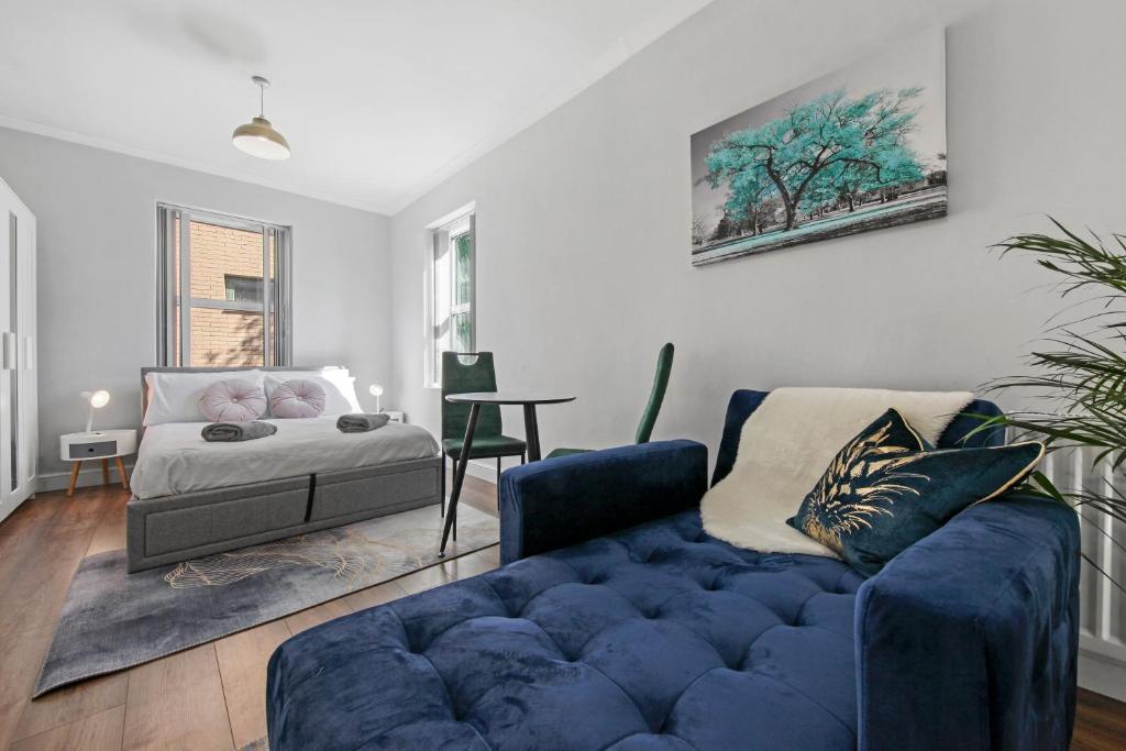 a living room with a blue couch and a bed at Stunning studio flat with free on-street parking! in Plumstead