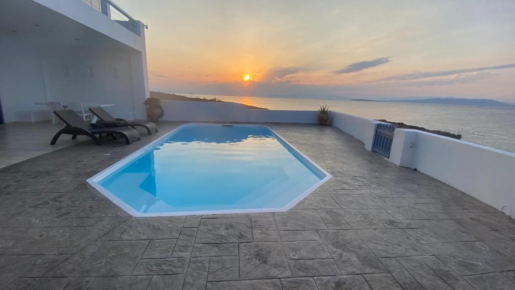 a swimming pool on the roof of a house with the sunset at NV Pool Villa in Áyioi