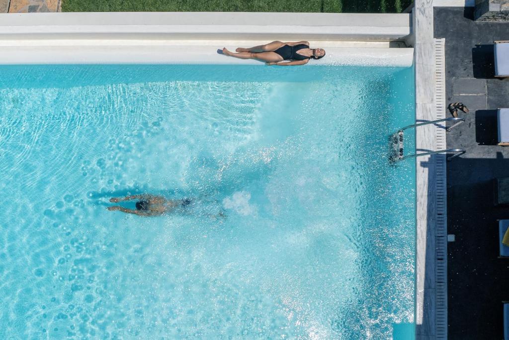 eine Person, die in einem Pool schwimmt in der Unterkunft Villa Dei Sogni, for the Design Lovers,By ThinkVilla in Kato Gouves