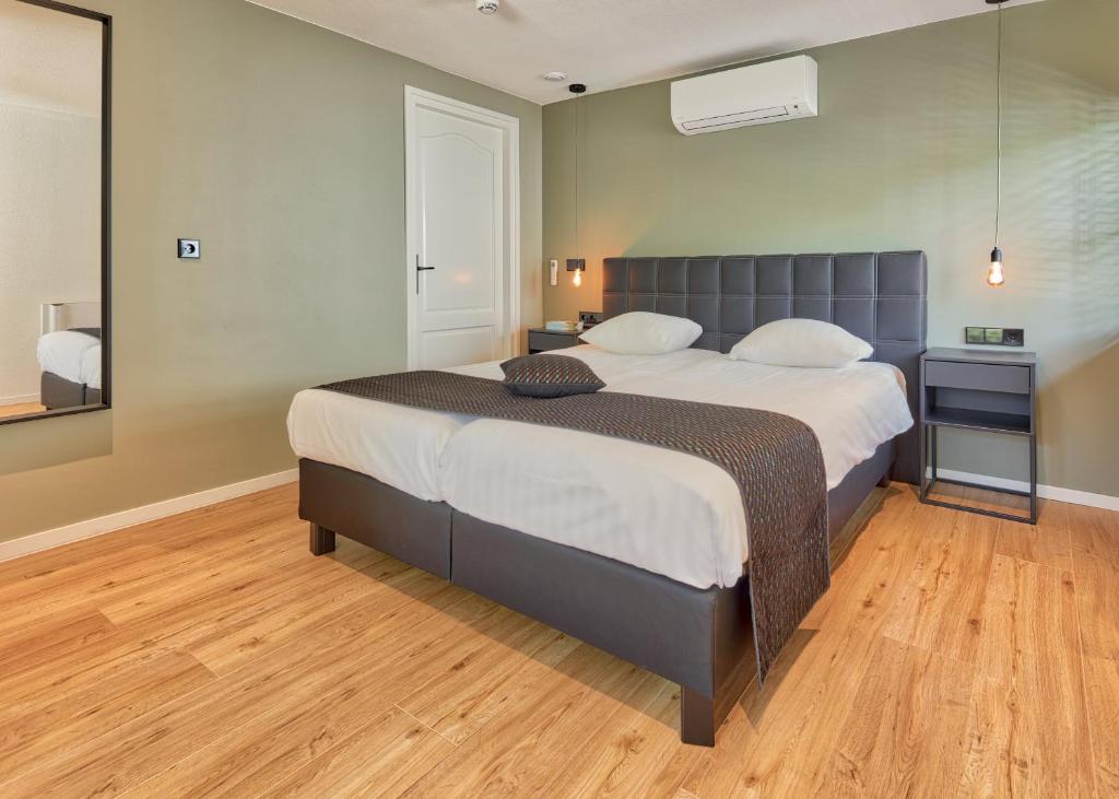 a bedroom with a large bed and a wooden floor at Hotel & Appartement de Zevende Heerlijkheid in Slenaken