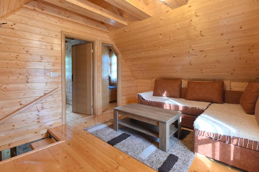een woonkamer in een blokhut met een bank en een tafel bij Vikendica pored Drine in Bajina Bašta