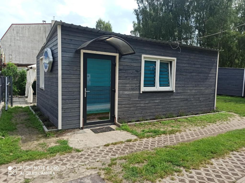 a small black house with a blue door at Domki u Radka in Łukęcin