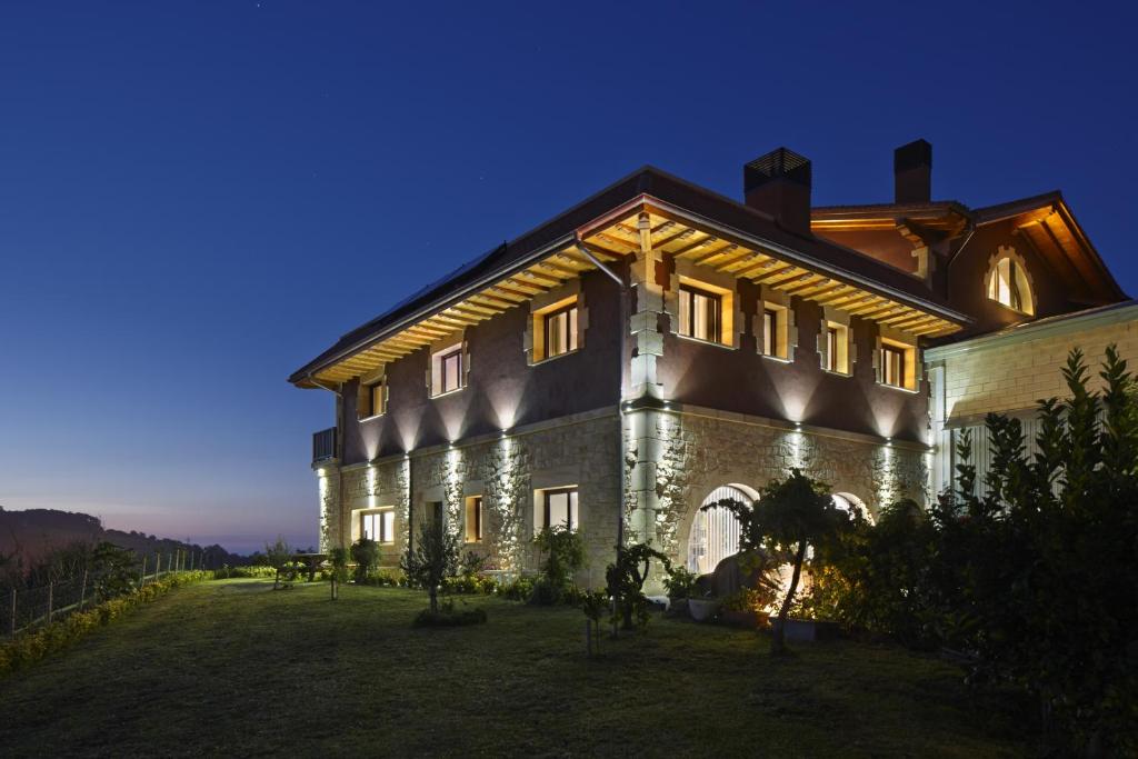 um grande edifício com luzes acesas à noite em Hotel Rural Gaintza em Getaria