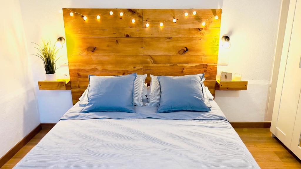 1 cama con almohadas azules y cabecero de madera en Apartamento La Playa, en Icod de los Vinos