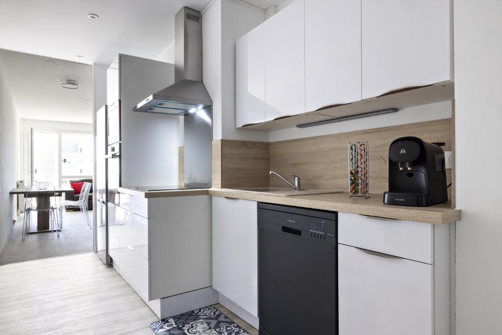 - une cuisine avec des placards blancs et un lave-vaisselle noir dans l'établissement LE COOL LEVEL, à Chalon-sur-Saône