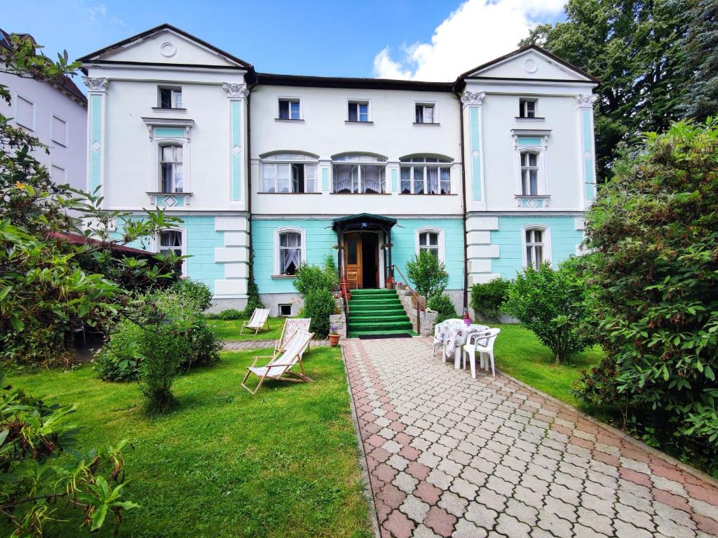 a large white building with a cobblestone yard at Willa Janina in Lądek-Zdrój