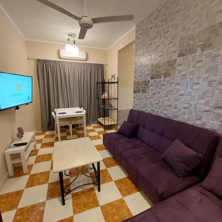 Il comprend un salon doté d'un canapé violet et d'une télévision à écran plat. dans l'établissement Coral flat with 2 bedrooms and 3 balconies ., à Marsa Alam