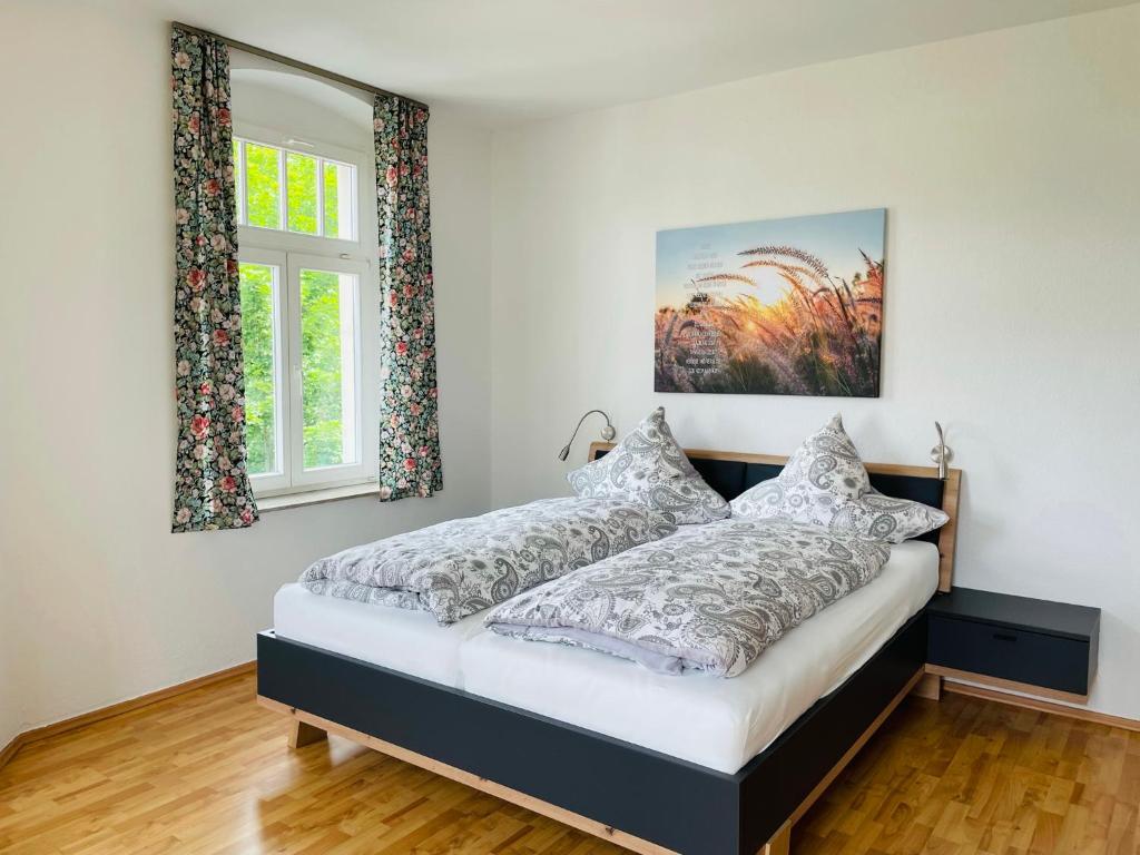 a bedroom with a bed and two windows at "Glück auf" Lichtdurchflutete schicke Ferienwohnung in Zwickau in Zwickau