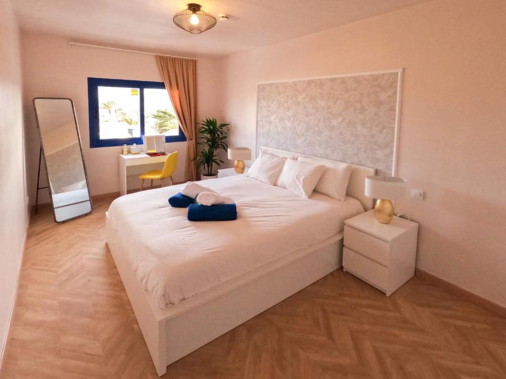 ein Schlafzimmer mit einem großen weißen Bett mit blauen Handtüchern darauf in der Unterkunft Arilvia good vibes only in Costa Calma