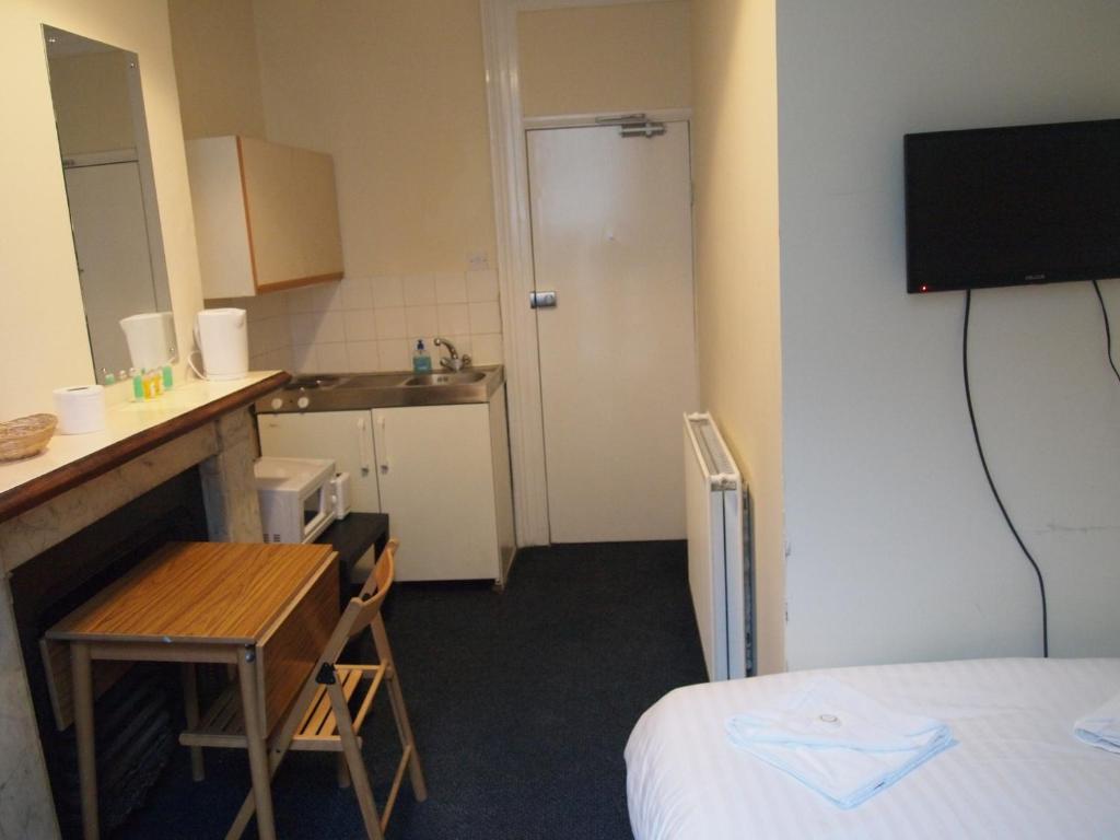 a small room with a bed and a small kitchen at Paddington Flats in London