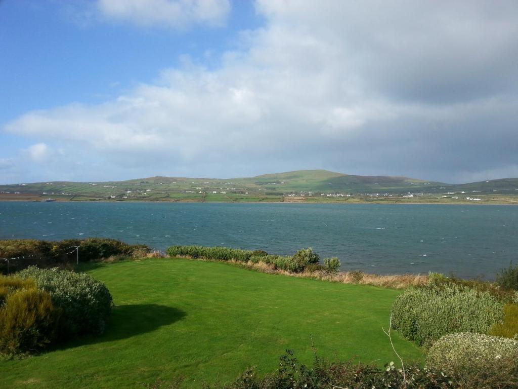 un campo verde junto a un cuerpo de agua en Portmagee Seaside Cottages, en Portmagee