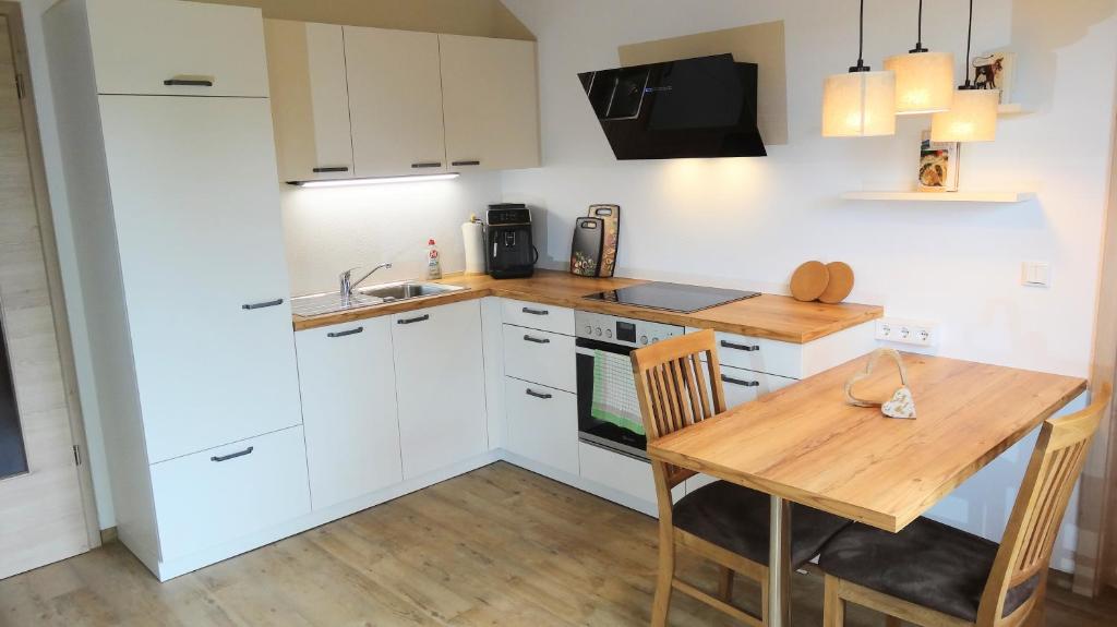 a kitchen with white cabinets and a wooden table at BachLauf im Happy Allgäu in Leutkirch im Allgäu