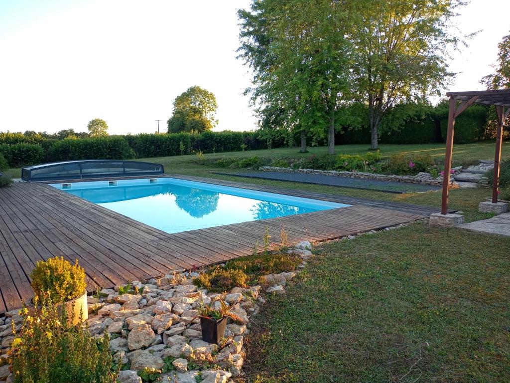 a swimming pool in a yard with a wooden deck at Au chant des oiseaux 