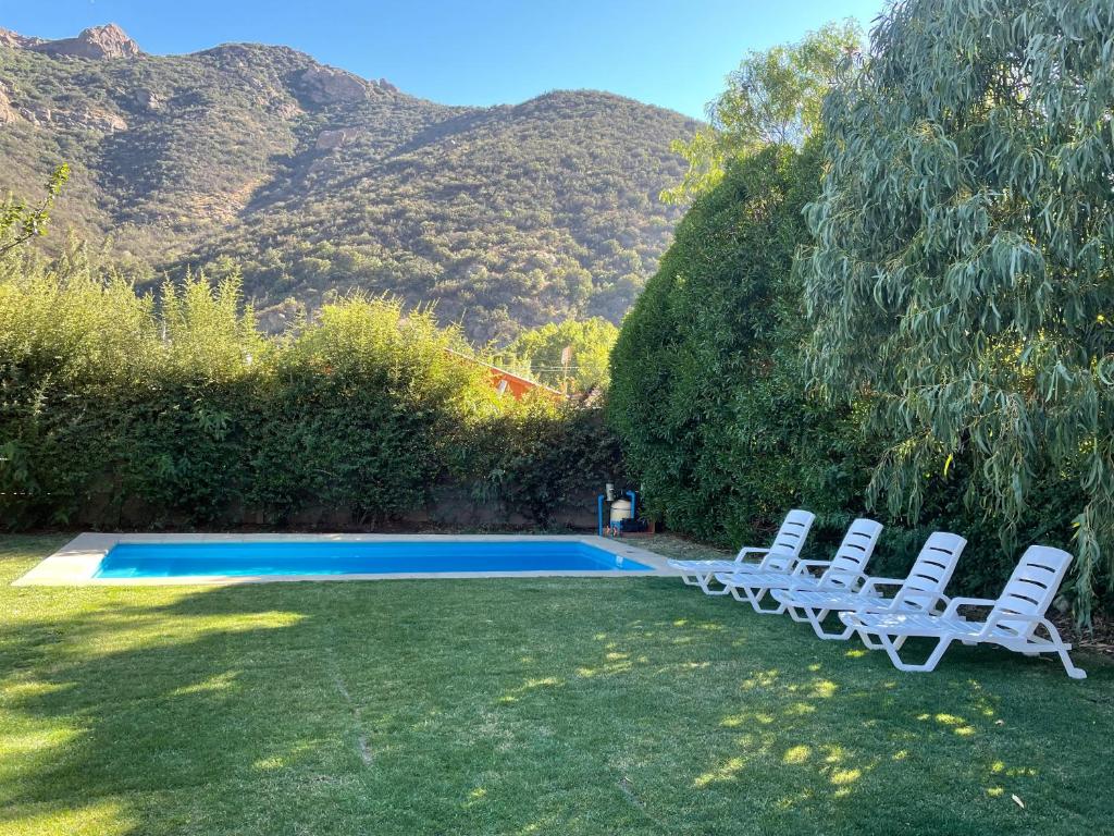 Cajon del Maipo的住宿－Linda casa en El Manzano con hermosa vista!!!，两把白色椅子坐在游泳池旁