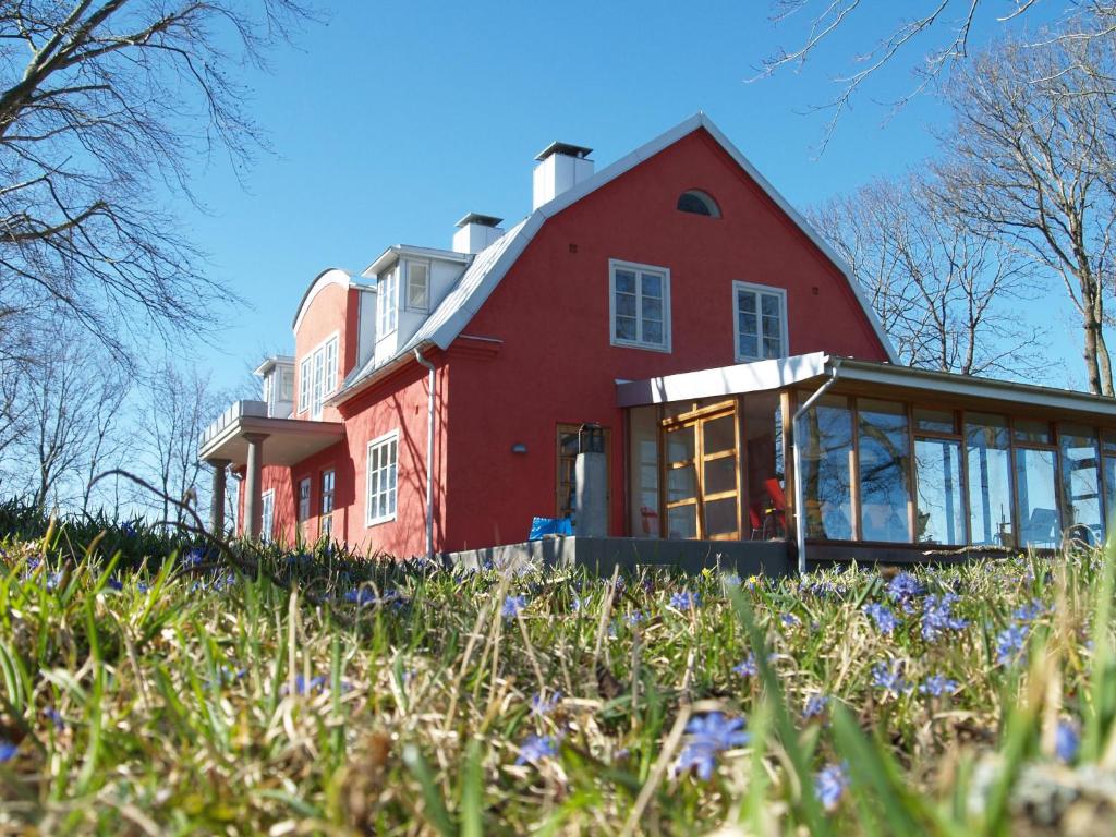a red house on top of a hill with purple flowers at Stora Topphem in Skåne-Tranås
