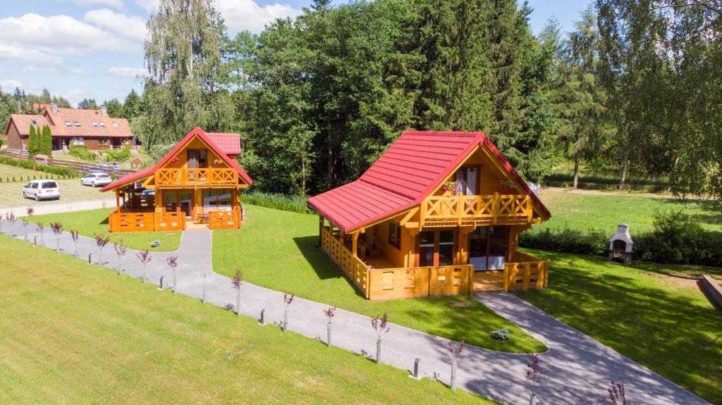 due case di tronchi con tetti rossi in un parco di Domki nad jeziorem Kolonia Rybacka a Kolonia Rybacka