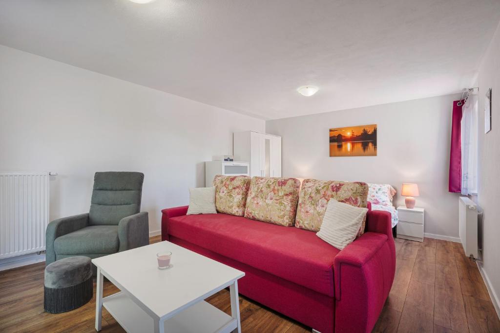 a living room with a red couch and a chair at Apartmán pod čerešňou in Banská Štiavnica